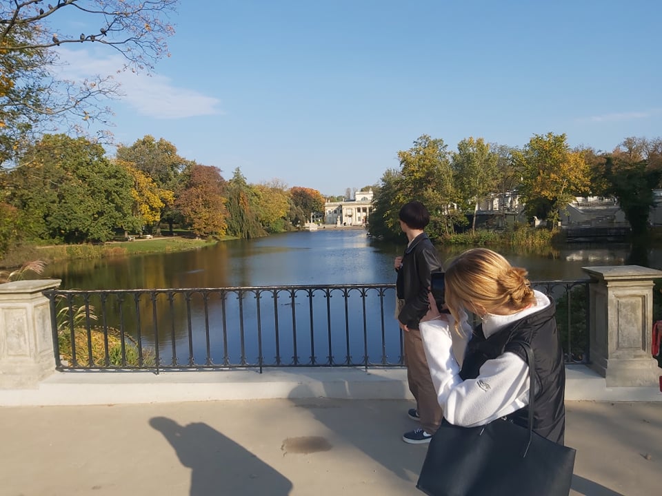 Młodzież w Łazienkach w Warszawie, widok na zamek na wodzie