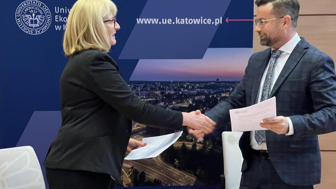 Na-zdjeciu-pani-dyrektor-w-budynku-Uniwersytetu-Ekonomicznego-w-Katowicach-podaje-dlon-rektorowi-UE-po-podpisaniu-umowy
