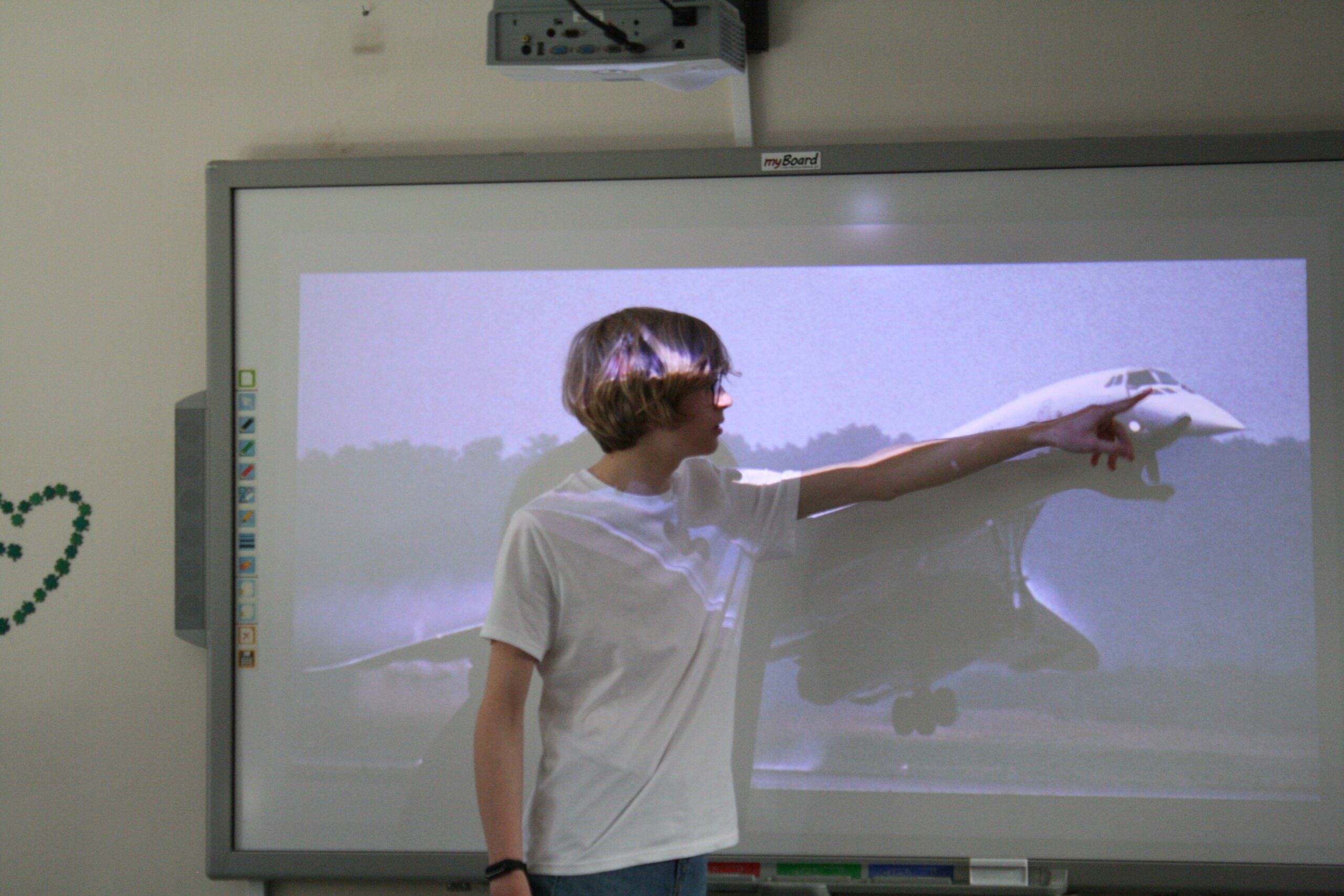 Uczeń klasy pierwszej przy tablicy interaktywnej prezentuje samoloty