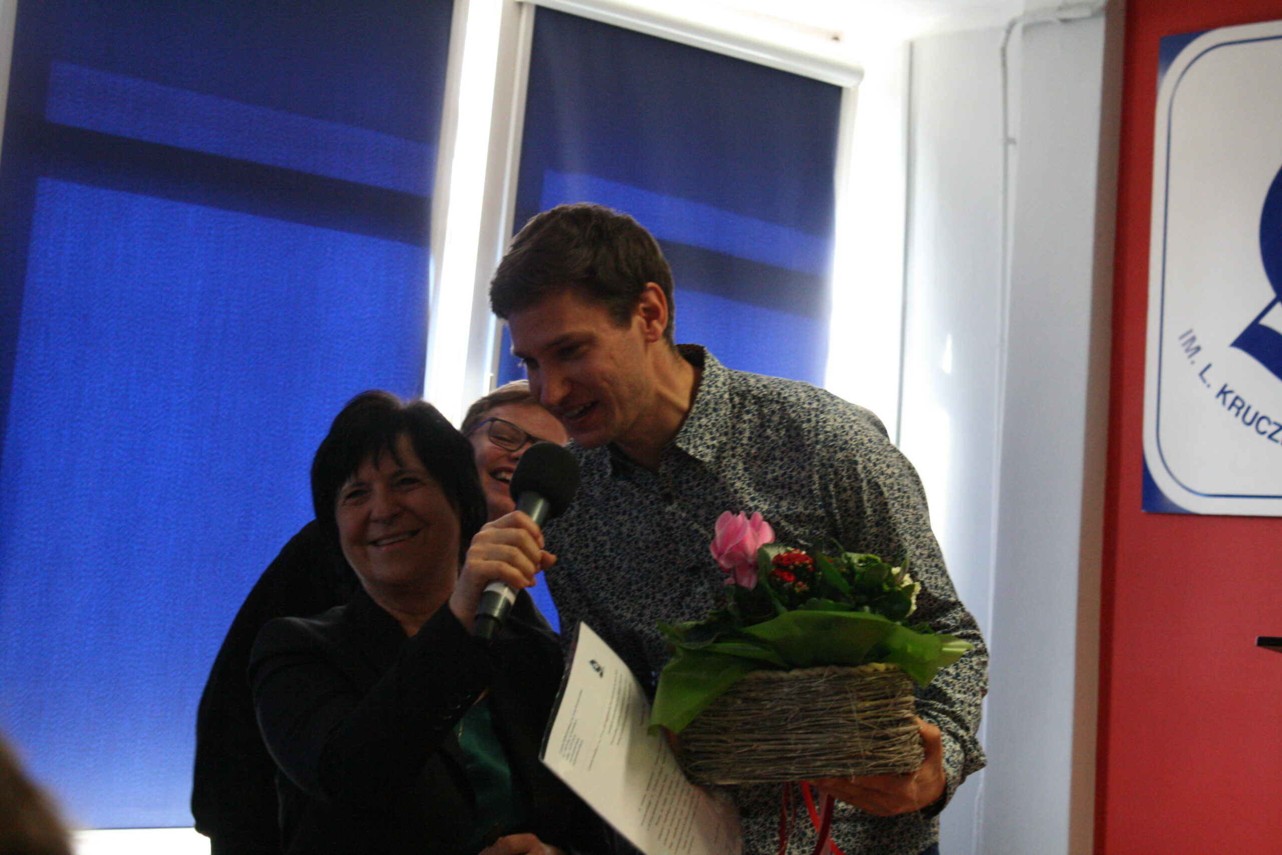 Wykładowcą z UŚ wraz z nauczycielką biologii, trzymają kwiaty i dyplom